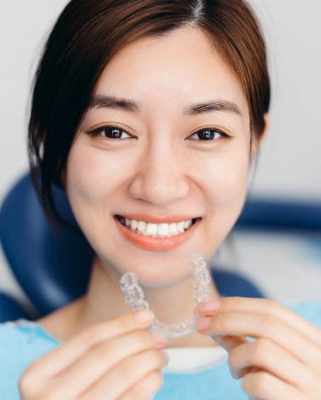 Happy teen patient showing Invisalign aligners at Uptown Charlotte dental office